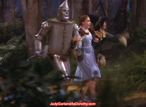 Judy Garland as Dorothy and her companions running through the forest