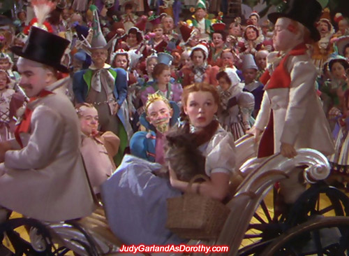 Judy Garland as Dorothy is transported in style around Munchkinland