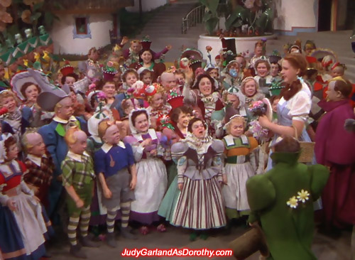 Judy Garland as Dorothy is welcomed by the Munchkins to their land in Oz