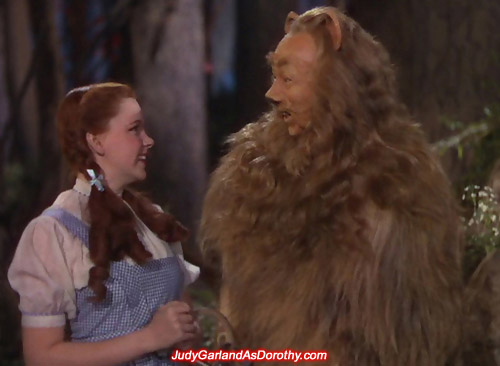 Judy Garland as Dorothy smiling at the Cowardly Lion